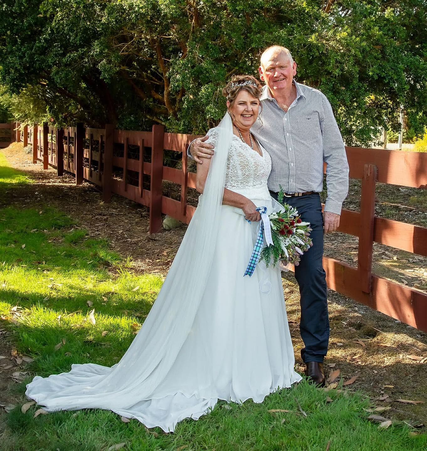 Bride in a lace-bodice gown with short sleeves and a long veil, standing with her groom